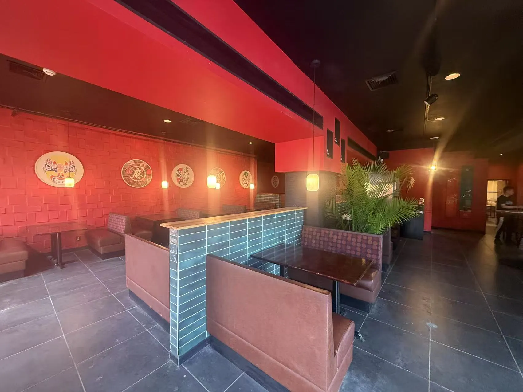 Spacious restaurant booth seating area with red brick walls and tropical greenery at Chengdu Impression Chinese Restaurant in Schenectady