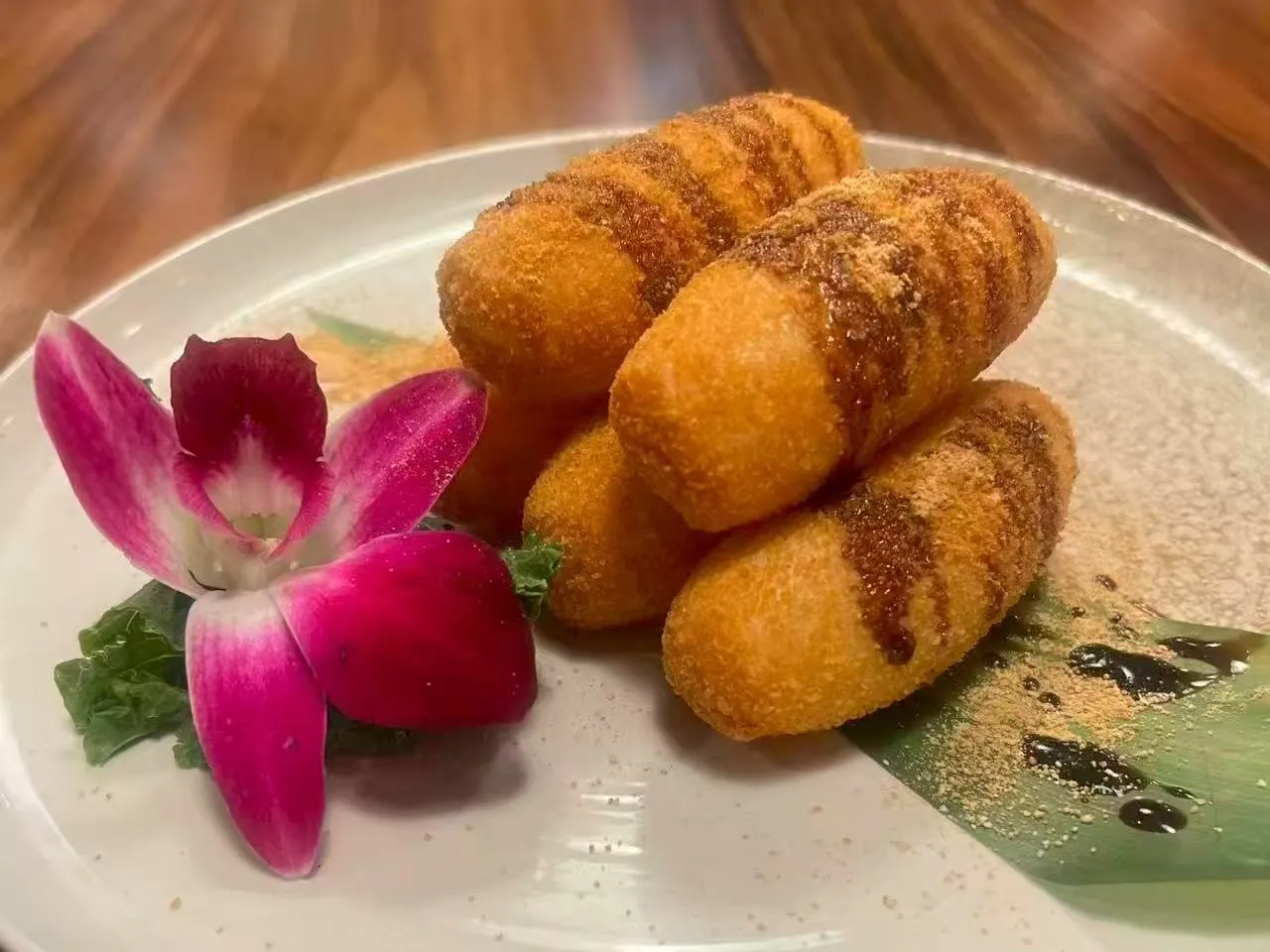 Fried crispy milk rolls drizzled with brown sauce and purple orchid garnish at Chengdu Impression Chinese Restaurant in Schenectady